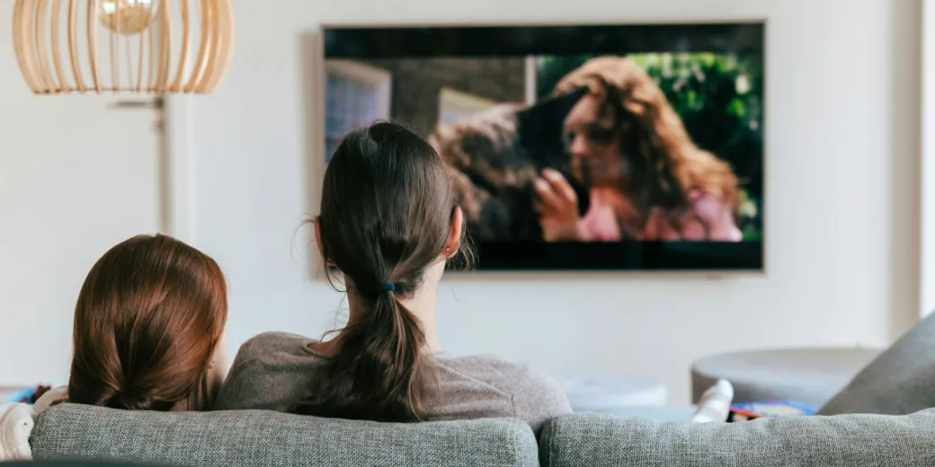 Two women sat on sofa watching tv